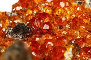 macro mineraal steen spessartine, oranje, rood granaat met kwarts Aan wit achtergrond foto