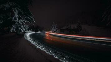 een lang blootstelling fotograaf van een besneeuwd weg Bij nacht foto