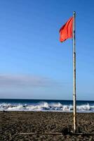 een rood vlag Aan de strand met golven in de achtergrond foto