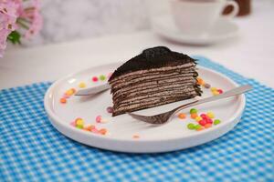 stuk van eigengemaakt chocola pannenkoeken taart Aan een wit bord foto
