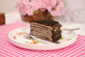 stuk van eigengemaakt chocola pannenkoeken taart Aan een wit bord foto