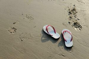 sandalen en schoenen voetafdrukken Aan de strand en blauw zee. foto