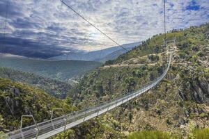 visie langs een indrukwekkend suspensie brug over- een diep vallei gedurende de dag foto
