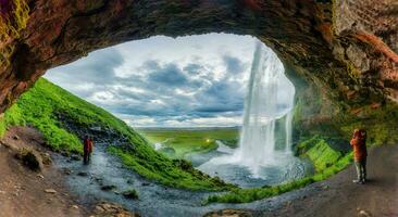 natuurlijk grot met seljalandsfoss waterval vloeiende en toerist genieten van in zomer Bij IJsland foto