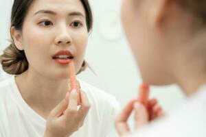 portret mooi Aziatisch vrouw zitten in voorkant van een spiegel en glimlach Aan verzinnen. gezicht van gezond vrouw van toepassing zijn verzinnen. advertentie, levensstijl , cosmetica, bedenken accessoires, schoonheid werkzaamheid, schoonheidsspecialist foto