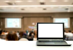 laptop Aan wit bureau met wazig publiek in congres bedrijf en voorraad foto