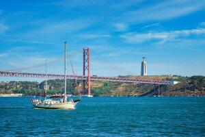 visie van 25 de abril brug over- tagus rivier, Christus de koning monument en een jacht boot. Lissabon, Portugal foto