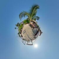 kokosnoot bomen in oerwoud in Indisch keerkring dorp Aan zee kust Aan weinig planeet in blauw lucht, transformatie van bolvormig 360 panorama. bolvormig abstract visie met kromming van ruimte. foto