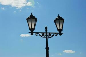 twee zwart wijnoogst straat lampen tegen een blauw lucht. foto