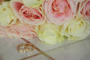 boeket met mooi wit en roze rozen en bruiloft ringen. foto