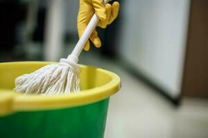 hand- Holding dweilen schoonmaak Bij keuken huis. genereren ai foto