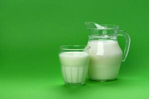 pot en glas van melk geïsoleerd Aan groen achtergrond met kopiëren ruimte voor tekst, zuivel Product concept foto