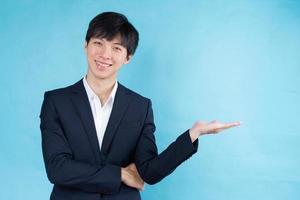 afbeelding van een jonge Aziatische zakenman die een pak draagt op een blauwe achtergrond foto