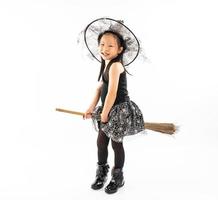 portret Aziatisch meisje gekleed in heks die op de bezem rijdt
