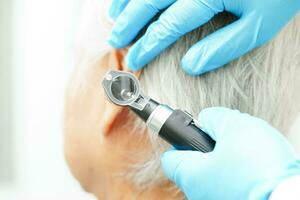 otolaryngoloog of ent arts dokter onderzoeken senior geduldig oor met otoscoop, horen verlies probleem. foto