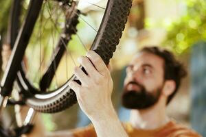 gedetailleerd schot van jong Mens Holding en aangrijpend fiets band rubber voor ontmanteling naar reparatie in tuin. beeld tonen detailopname van persoon hand- grijpen beschadigd fiets rubber buis voor bevestigen. foto