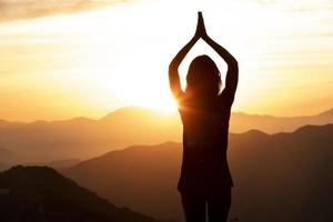 vrouw die yoga doet bij zonsondergang foto