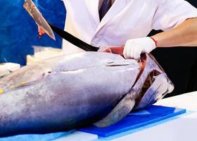 professionele Japanse chef-kok die verse tonijn snijdt in een restaurant foto