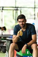 jonge man traint in de sportschool en eet bananen voordat hij gaat sporten.