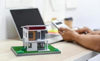 model huis met wazige achtergrond van een persoon met behulp van rekenmachine. foto
