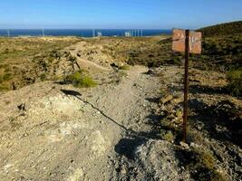 een teken Aan de kant van een aarde weg in de buurt de oceaan foto