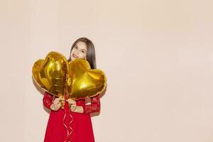 vrouw houdt hart vormig gouden lucht ballonnen. valentijnsdag dag, verjaardag, vrouwen dag, verjaardag, vakantie viering concept foto