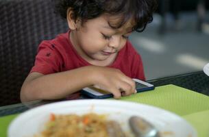 jongens Doen niet eten voedsel omdat ze Speel smartphones foto