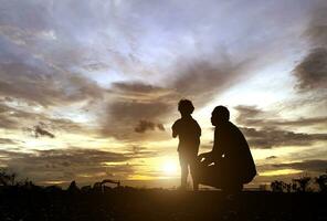 de silhouet van de vader en zoon wie genoten de zonsondergang voor vader dag liefdesvakantie concept foto