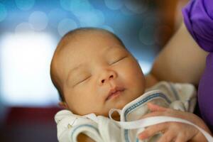 2 weken oud Aziatisch vrouw baby wezen in haar moeder armen foto