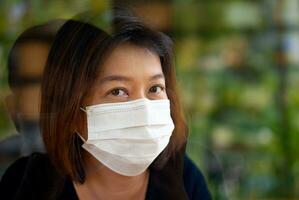 Aziatisch vrouw vervelend beschermend masker Aan haar gezicht foto