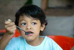 Aziatisch jongen is aan het eten brownies foto