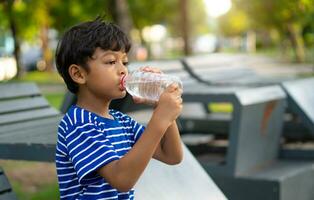 kind drinken water van een transparant plastic fles. foto