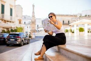 vrouw toerist met stad kaart door de heilige oronzo standbeeld in ostuni, Italië foto