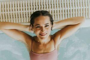 jong vrouw ontspannende in de binnen- zwemmen zwembad foto