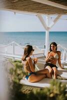 glimlachen jong Dames in bikini genieten van vakantie Aan de strand foto