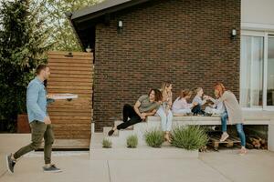 groep van jong mensen en kinderen voorbereidingen treffen voor aan het eten pizza in de huis achtertuin foto