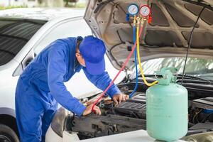 klusjesman controleren en gemaakt auto lucht conditioner systeem, technicus gecontroleerd auto lucht conditioning systeem koelmiddel opladen, lucht conditioning reparatie foto