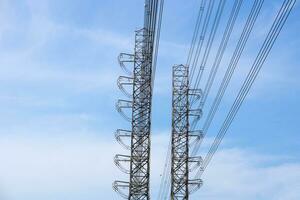 hoog voltage van macht transmissie torens Aan blauw lucht achtergrond foto