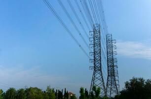 hoog voltage van macht transmissie torens Aan blauw lucht achtergrond foto