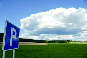 een parkeren teken in voorkant van een groen veld- foto