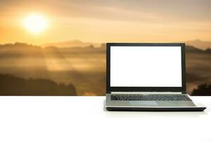 laptop Aan wit bureau met wazig tafereel zonlicht schijnen Aan berg Bij zonsopkomst foto