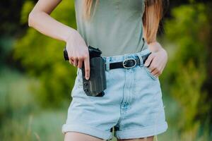 een meisje in denim shorts en met een pistool in haar hand- poses voor een foto.. detailopname foto