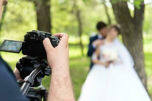 de videograaf schiet de getrouwd in de tuin in de zomer. foto