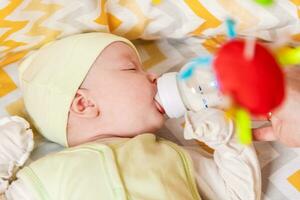 moeder feeds een pasgeboren baby met melk van een fles foto