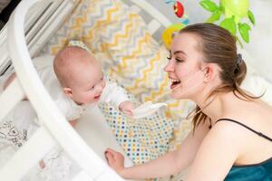 de baby probeert naar scheur uit de beschermend masker van haar moeder s gezicht gedurende de coronovirus en covid-19 pandemie. foto