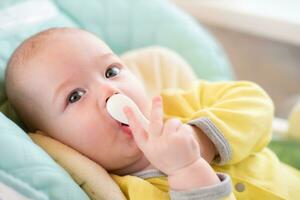 invoering van complementair voedingsmiddelen. de baby zullen eten kinderen voeding. kleuter met een lepel in een hoog stoel voor voeden. foto