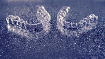 transparant aligners, tand vasthouders liggen Aan glas met water druppels foto