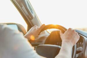 een Mens zit achter de wiel van zijn auto Aan een zonnig dag foto