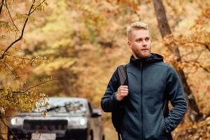 Mens reiziger Aan de achtergrond van een auto in de herfst Woud foto