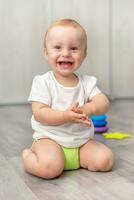 schattig baby lachend terwijl zittend Aan de verdieping foto